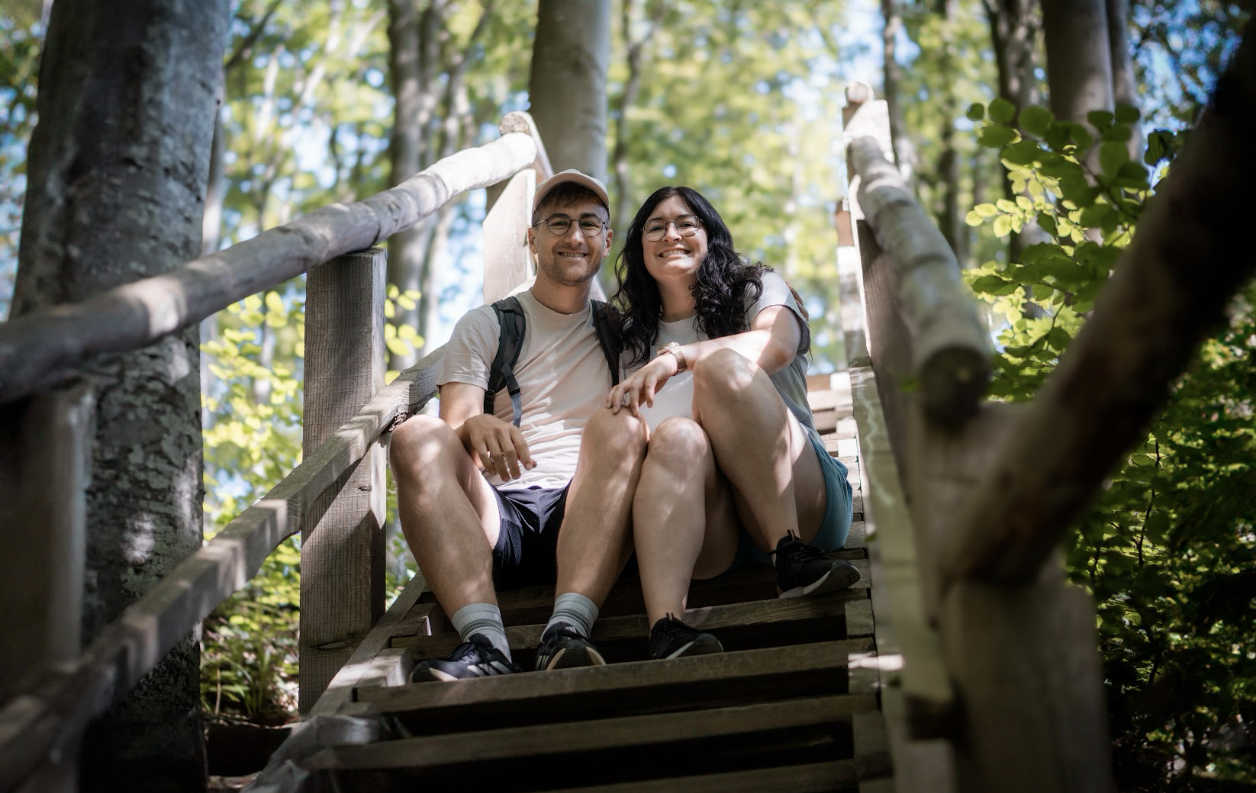 Elisa & Philipp, die auf einer Holztreppe sitzen und lächeln